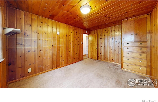 empty room with wooden walls, wood ceiling, and carpet flooring