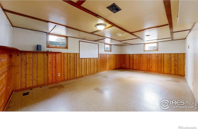 below grade area with tile patterned floors, wooden walls, wainscoting, and visible vents