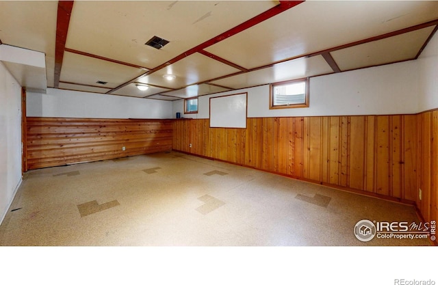 basement with visible vents, a wainscoted wall, and wood walls