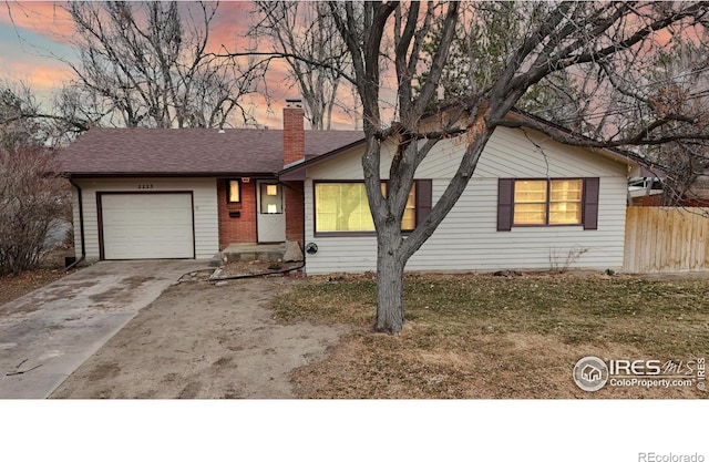 ranch-style home featuring brick siding, fence, a chimney, a garage, and driveway