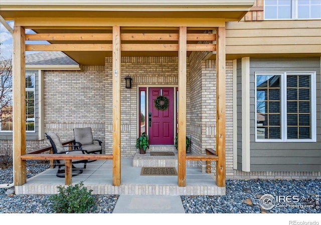 entrance to property featuring brick siding and a porch