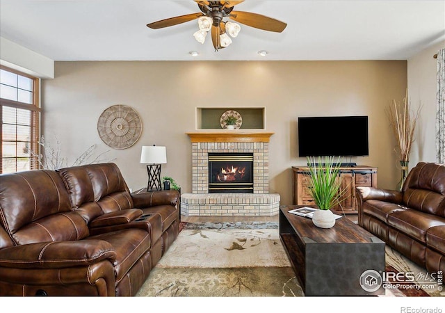 living area with a ceiling fan and a fireplace