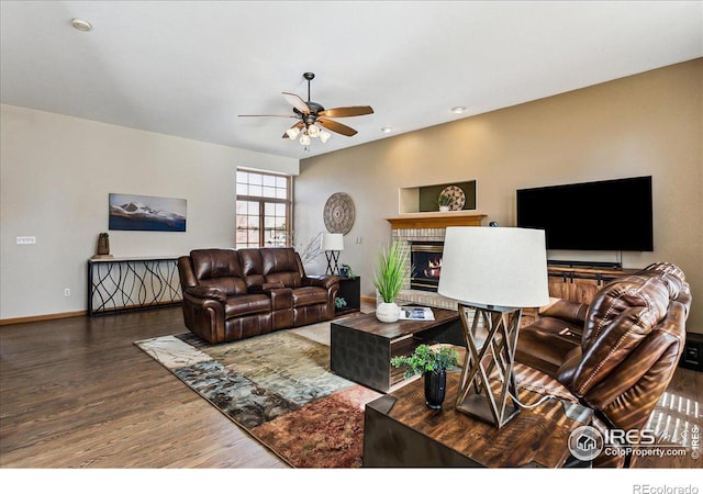 living area with a fireplace, wood finished floors, baseboards, and ceiling fan