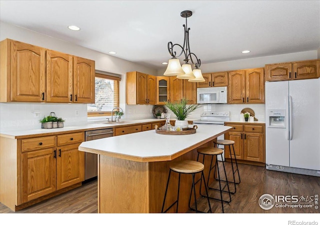 kitchen with dark wood finished floors, white appliances, a center island, and light countertops