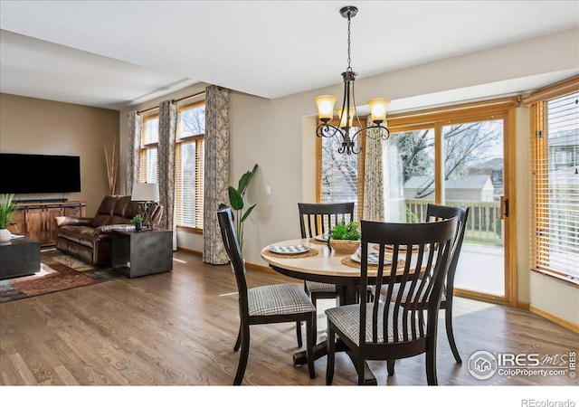 dining area with baseboards, an inviting chandelier, and wood finished floors