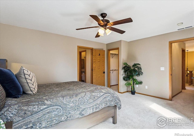 carpeted bedroom with visible vents, baseboards, a walk in closet, and a ceiling fan