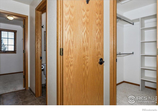 hallway featuring tile patterned flooring, carpet flooring, and baseboards