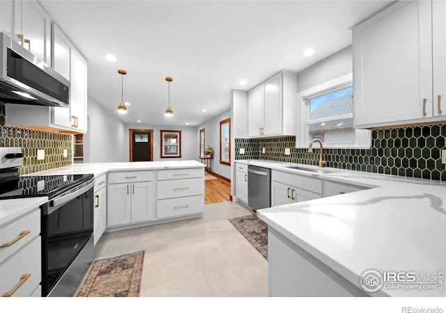 kitchen featuring a peninsula, recessed lighting, a sink, white cabinets, and appliances with stainless steel finishes