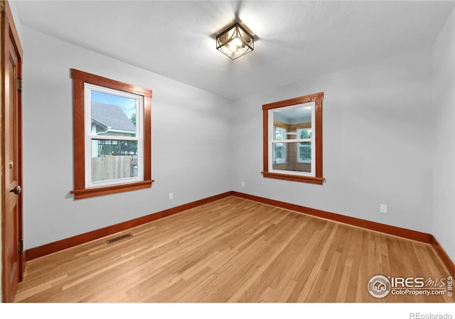 unfurnished room with visible vents, light wood-type flooring, and baseboards