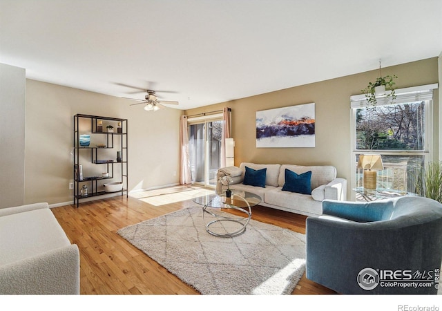 living area featuring light wood-style floors, baseboards, and ceiling fan