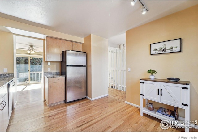 kitchen with a ceiling fan, baseboards, freestanding refrigerator, rail lighting, and light wood-style floors