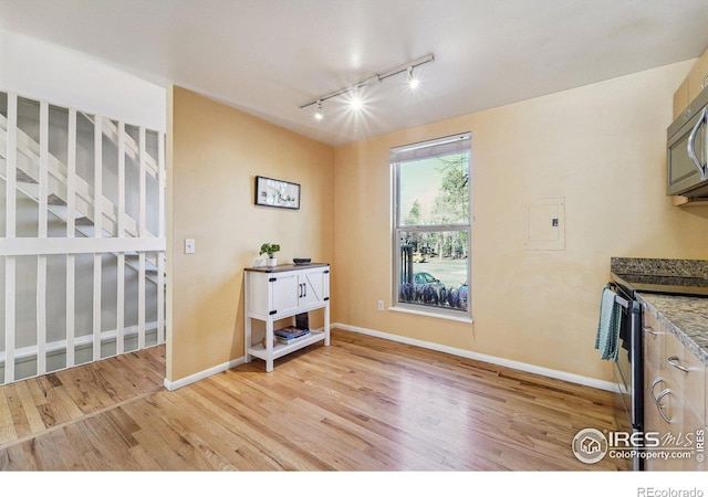 kitchen with light wood-type flooring, baseboards, black range with electric stovetop, and stainless steel microwave