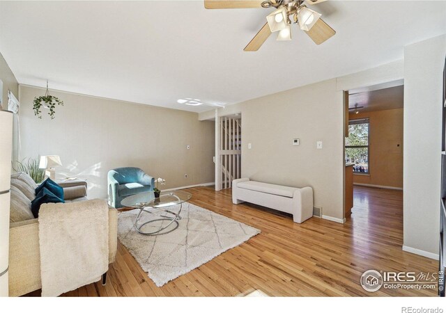 living room featuring a ceiling fan, baseboards, and wood finished floors