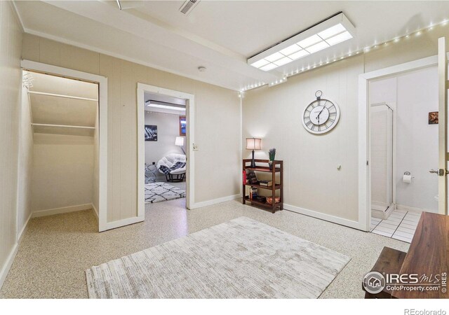 bedroom with visible vents, speckled floor, ensuite bathroom, and baseboards