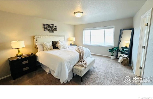 bedroom with dark colored carpet, baseboards, and a textured ceiling