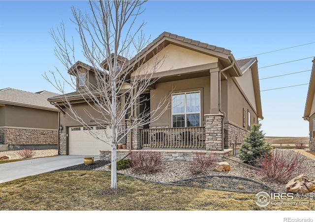 view of front of property with stone siding, stucco siding, a porch, and concrete driveway