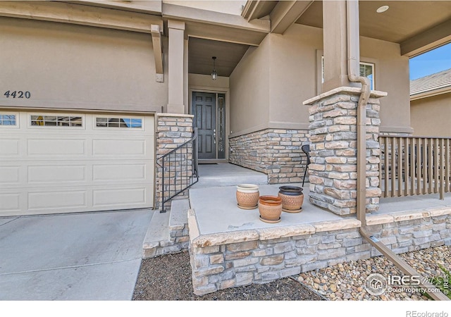 view of exterior entry with a garage, stone siding, and stucco siding