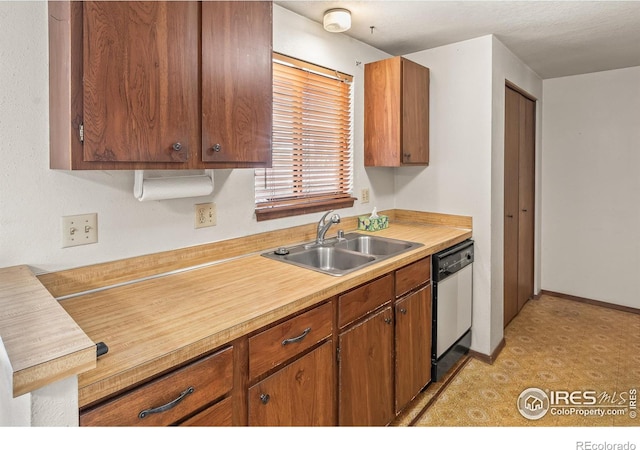 kitchen with light floors, dishwasher, light countertops, brown cabinetry, and a sink