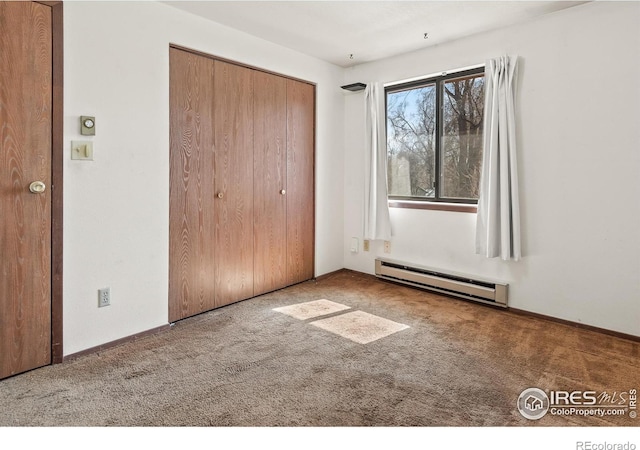 unfurnished bedroom with a closet, baseboards, baseboard heating, and carpet flooring