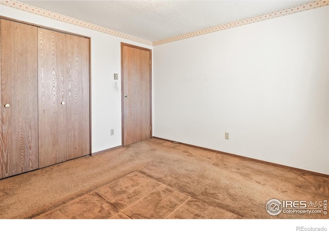 unfurnished bedroom with baseboards, multiple closets, a textured ceiling, and carpet flooring