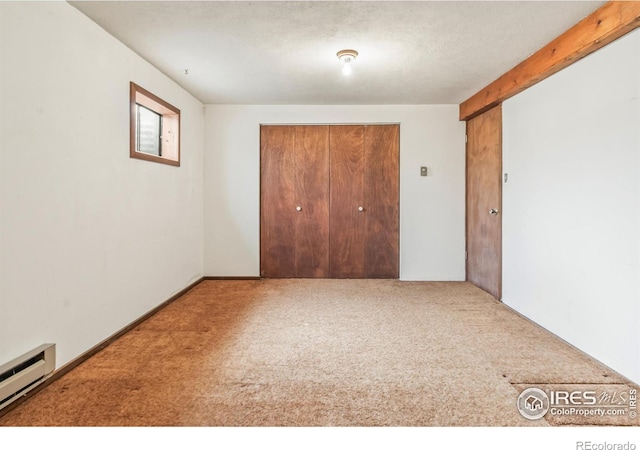 unfurnished bedroom with carpet, beam ceiling, a closet, a textured ceiling, and a baseboard radiator