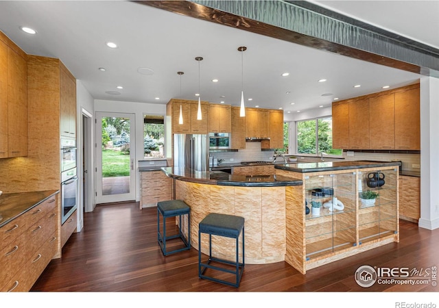 kitchen with brown cabinets, dark countertops, tasteful backsplash, stainless steel appliances, and dark wood-style flooring