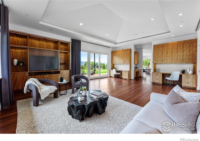 living room with recessed lighting, a tray ceiling, dark wood-style flooring, and built in study area