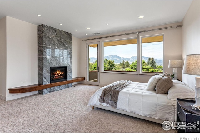 carpeted bedroom with access to exterior, recessed lighting, a mountain view, and a high end fireplace