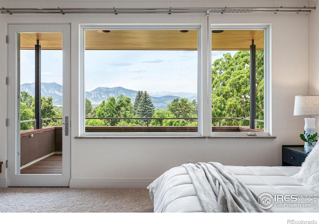 carpeted bedroom featuring a mountain view, multiple windows, and baseboards