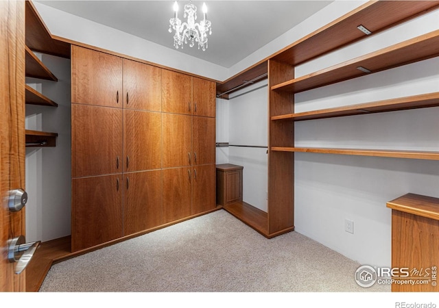 walk in closet featuring an inviting chandelier and carpet flooring