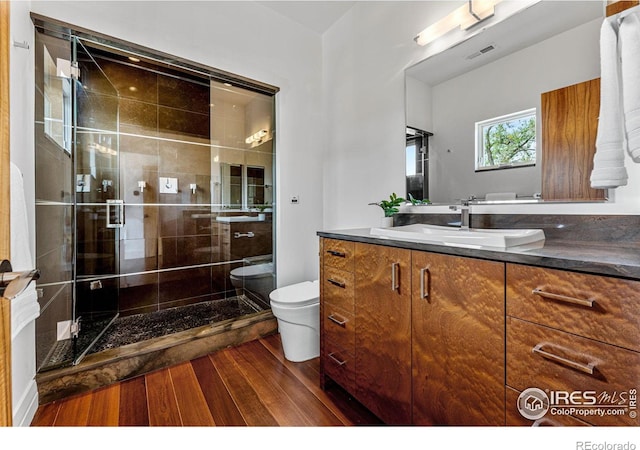 bathroom featuring vanity, wood finished floors, visible vents, a stall shower, and toilet