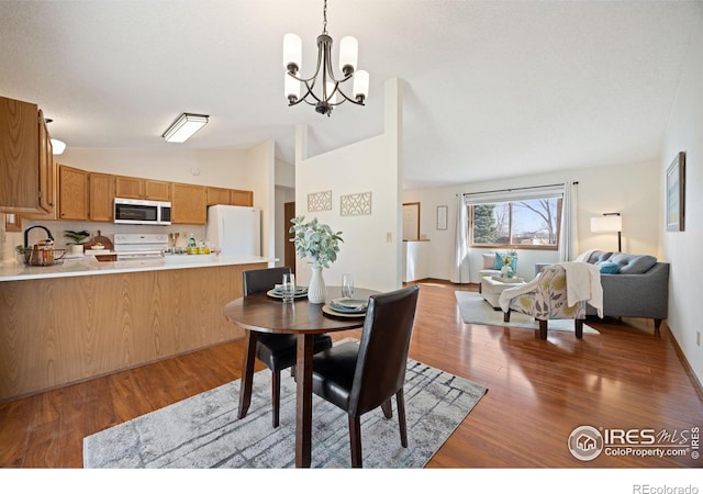 dining area with a chandelier, lofted ceiling, and wood finished floors