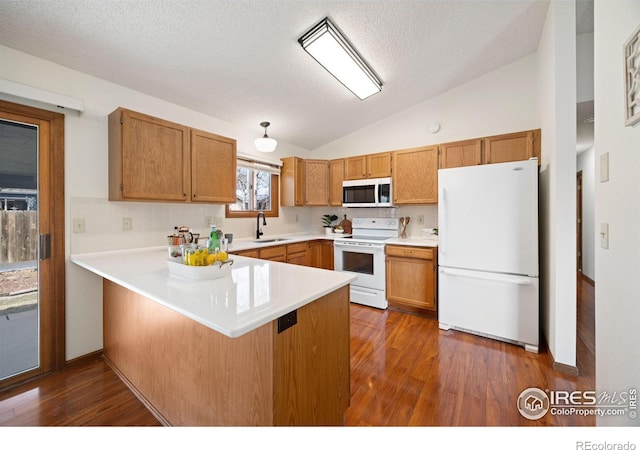 kitchen featuring a sink, white appliances, a peninsula, light countertops, and lofted ceiling