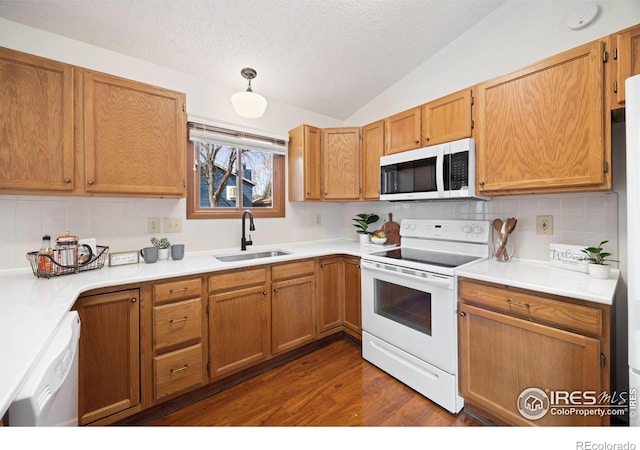 kitchen with lofted ceiling, dark wood-style floors, white appliances, a textured ceiling, and a sink