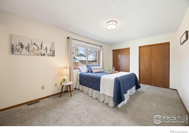 bedroom with baseboards, visible vents, two closets, and carpet