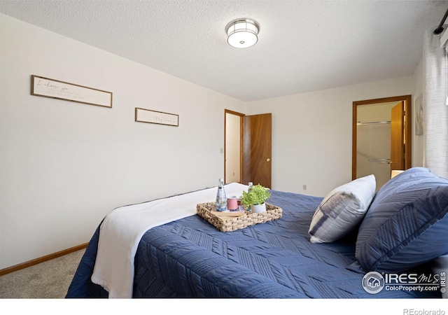 bedroom featuring baseboards, a textured ceiling, and carpet