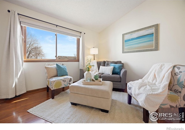 living room with a textured ceiling, wood finished floors, and vaulted ceiling