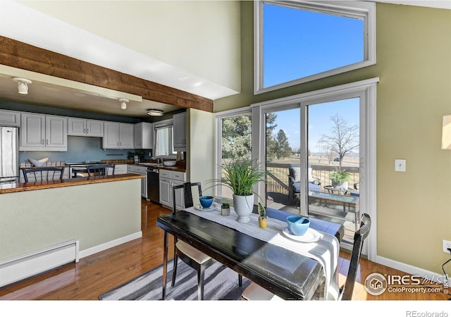 dining space featuring beamed ceiling, dark wood-type flooring, baseboards, and a baseboard radiator