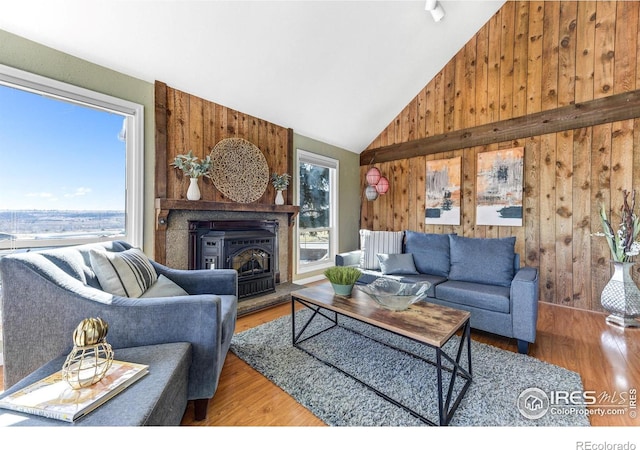 living area with wood finished floors, wood walls, and high vaulted ceiling