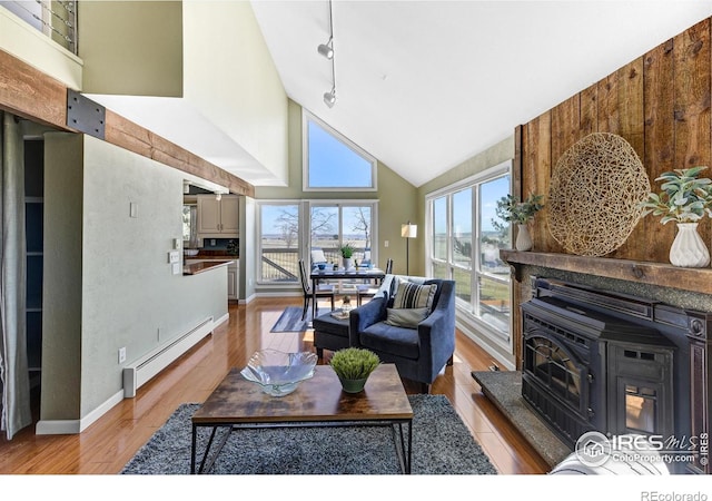 living room with a baseboard heating unit, high vaulted ceiling, rail lighting, and light wood finished floors