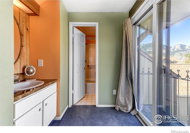 full bathroom featuring a mountain view, baseboards, a tub to relax in, and vanity