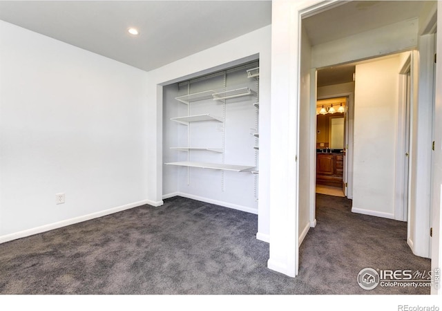 unfurnished bedroom featuring recessed lighting, baseboards, dark colored carpet, and a closet