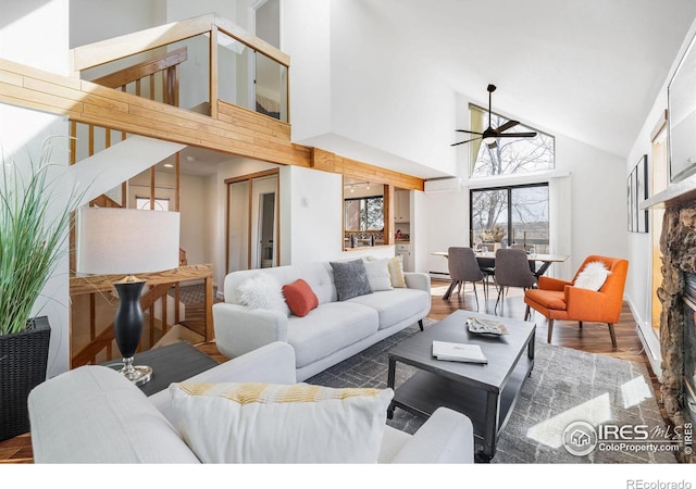 living area with a ceiling fan, wood finished floors, high vaulted ceiling, a fireplace, and a wall mounted air conditioner