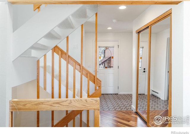 stairway with recessed lighting, wood finished floors, baseboards, and a baseboard radiator