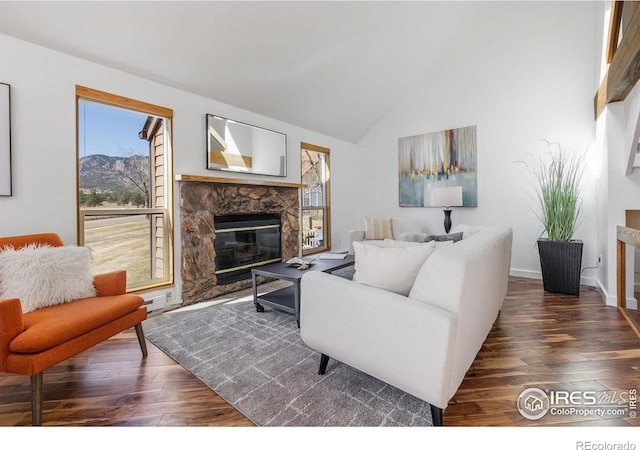 living area featuring a stone fireplace, high vaulted ceiling, baseboards, and wood-type flooring