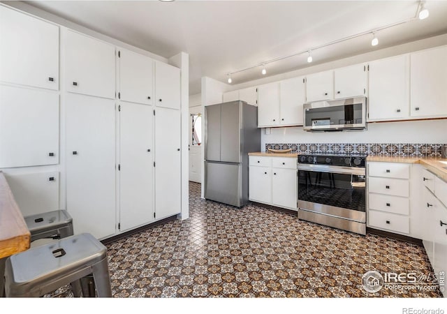 kitchen with stainless steel appliances, white cabinets, and dark floors