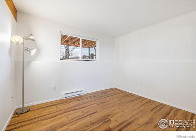 unfurnished room featuring wood finished floors, baseboards, and baseboard heating