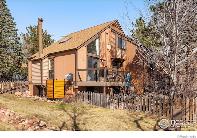 rear view of property with stairway, a shingled roof, a deck, and fence