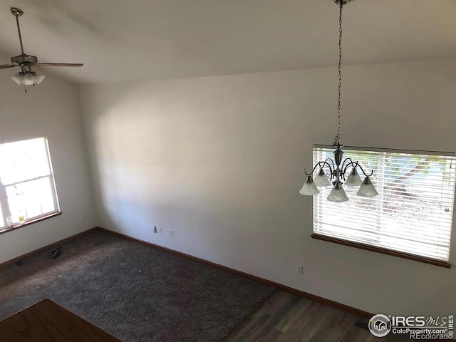 spare room with dark wood-type flooring, ceiling fan with notable chandelier, and baseboards