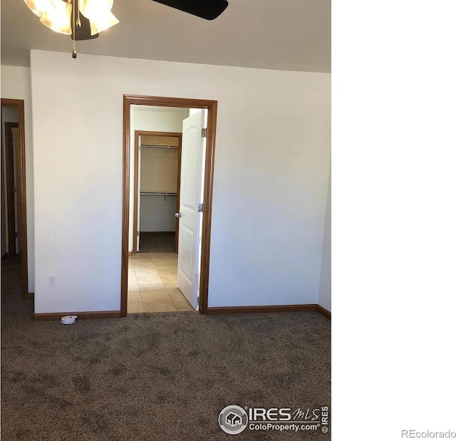 spare room featuring light tile patterned floors, baseboards, light colored carpet, and ceiling fan